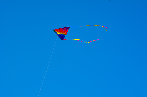 Rainbow-colored kite flying high at the beach, Orange Beach, Alabama