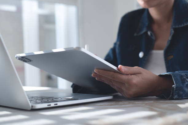 istock Close up business woman using digital tablet with laptop computer on tablet at office. Young casual woman online working on computer devices from home office, telework, telecommuting 1433716220