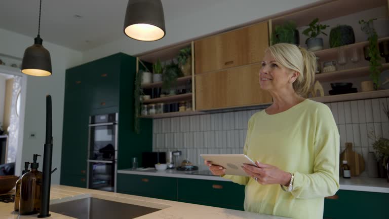 Happy senior woman controlling the lights of her smart home with a mobile app on her tablet