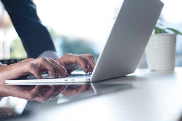 istock Businessman hands typing, working on laptop computer with digital tablet on white office table. Man manager surfing the internet, searching the information 1433717510