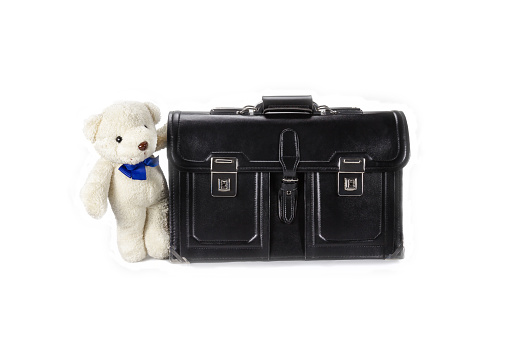 Black retro leather schoolbag with teddy bear on background