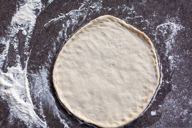istock Rolled out pizza dough on floured slate surface, photographed overhead 1433724103