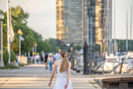 Chicago, IL - September 19, 2022: A young woman goes for a walk on the Lakefront Trail, along Lake Michigan, downtown in the loop, with the city skyline in the distance.