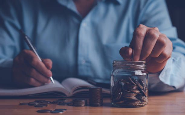 istock Hand putting coins into the jar and stack coin on wood table. 1433740593