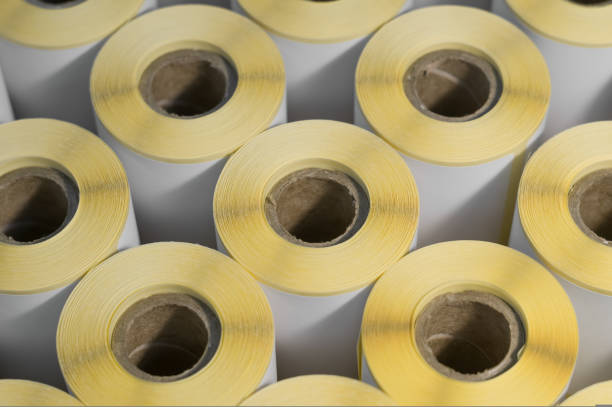 istock Rollers with a white self-adhesive label for printing labeling information. Ribbon with white label on cardboard spools. Products of the printing house. Selective focus 1433744622