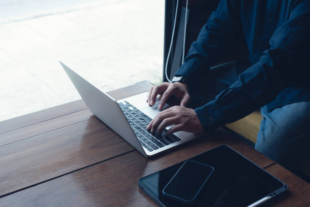 istock Man working on laptop computer and using digital tablet surfing the internet on wooden table at coffee shop 1433746837