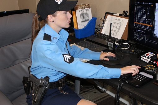 lone female police officer in office checking computer, radio, crime scene