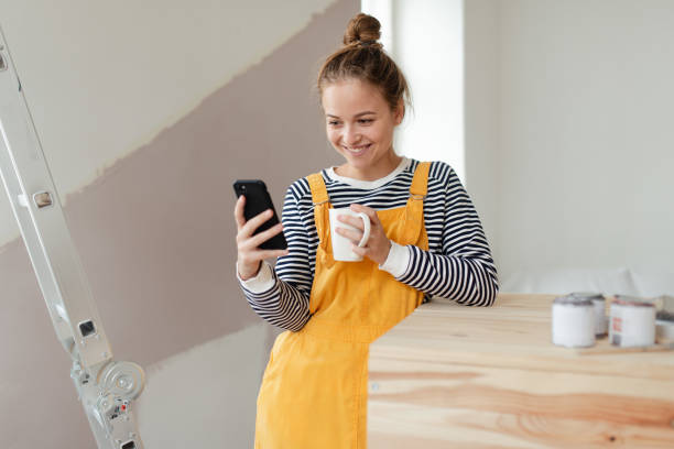 istock Happy young woman having break during renovation her aparatment. Using phone, searching inspiration at social medias. 1433752173