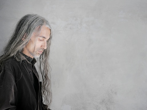 Man with silver hair and black shirt looking down