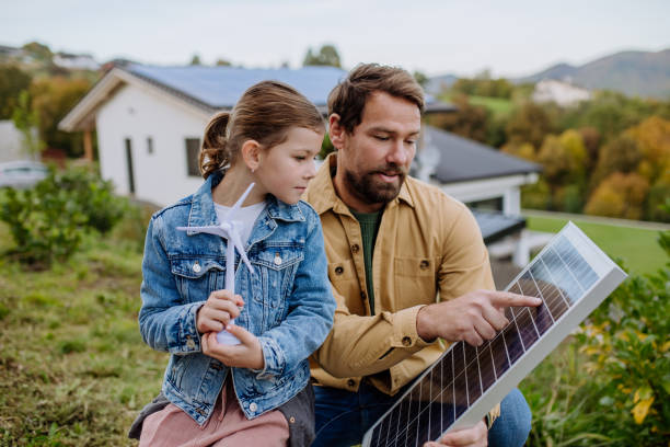 Father showing his little daughter solar photovoltaics panels, explaining how it works. Alternative energy, saving resources and sustainable lifestyle concept. stock photo