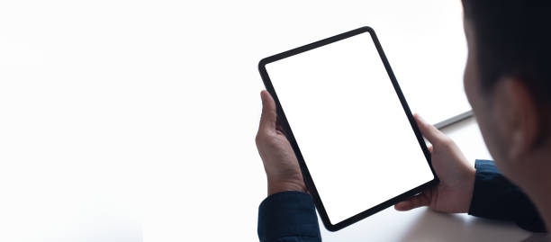 Mockup image of man's hand holding black white screen digital tablet on white black ground, over shoulder view