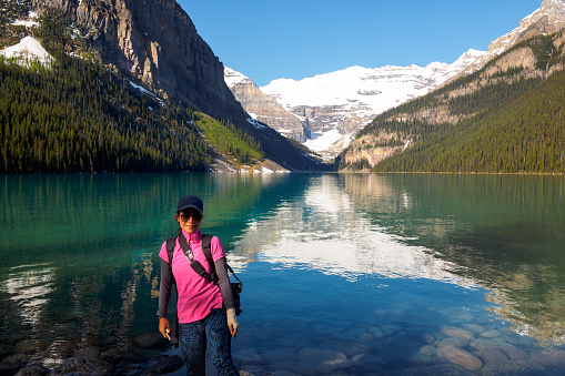 A tourist woman standing by the lake enjoying the spectacular landscape in Banff National Park