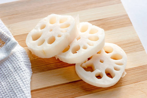 台所の木製まな板の上の白いレンコン(レンコン)スライスの接写 - lotus root 写真 ストックフォトと画像