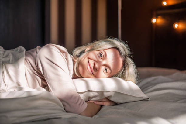 istock Happy middle aged woman sits on bed and stretching arms 1433771049