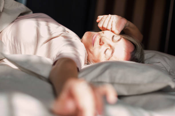 istock Happy middle aged woman sits on bed and stretching arms 1433771052