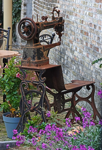 Rusty old sewing machine placed in front of the house as a decoration. Some flower pots and rusted deco define a sort of front garden. Located in Harlingen, the Netherlands
