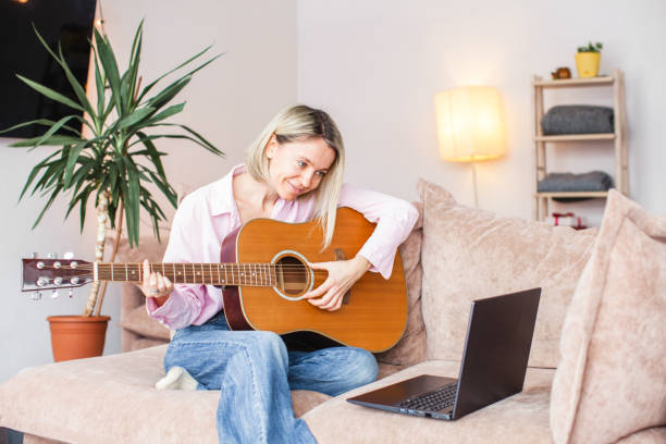 istock Middle aged woman practicing and learning how to play guitar on laptop 1433772498