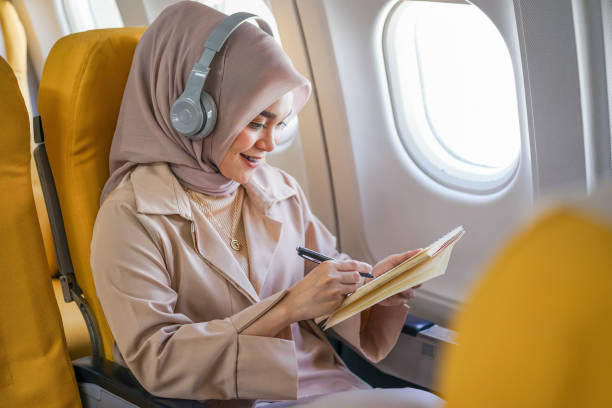istock Beautiful asian muslim woman passengers wearing wireless headphone and writing on notebook during on the flight. 1433777620