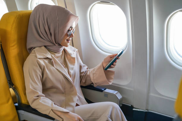 istock Beautiful muslim woman using mobile phone in airplane. 1433777622