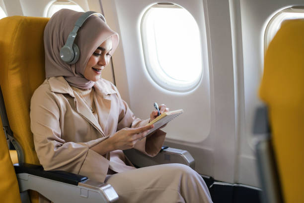 istock Beautiful asian muslim woman passengers wearing wireless headphone and writing on notebook. 1433778043