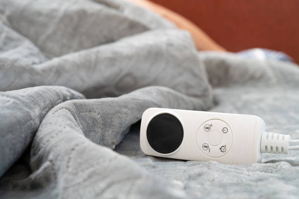 controller of an electric blanket with a human sleeping at the background at horizontal composition stock photo