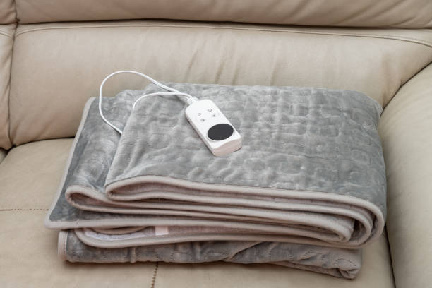 folded electric blanket with controller on a sofa stock photo