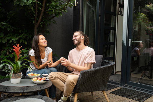 Man gently holds the hands of a charming woman, the female sits in a cozy hanging chair