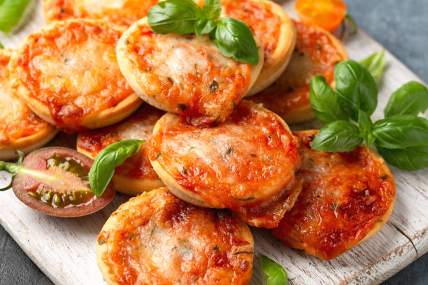 istock Mini pizzas with tomatoes and mozzarella cheese on white wooden board 1433784179