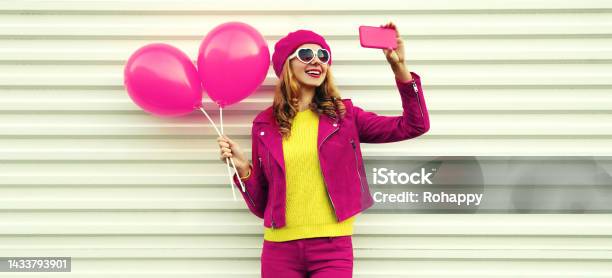 Portrait Of Happy Smiling Young Woman Taking Selfie With Phone Holding Pink Balloons Wearing Beret On White Background Stock Photo - Download Image Now