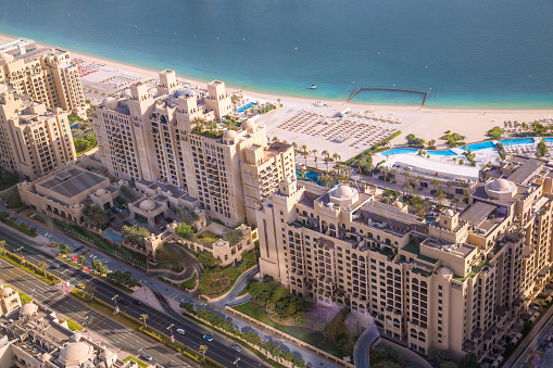 Dubai Marina apartments complex at sunset view with beaches. Yachts and speed boats on the pier. Dubai, UAE