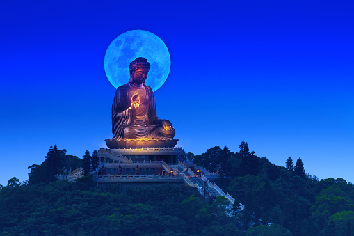The round moon rises just behind the Buddha's head at Lantau Island.