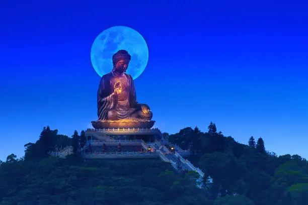 Photo of The full moon rises just behind the Buddha's head