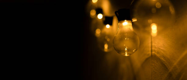 istock Hanging electric light bulbs on the wall against a black background with copy space. 1433802343