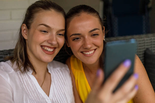 istock Sisters sitting on balcony, taking selfies with mobile phone 1433806497