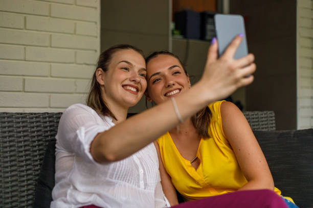 istock Sisters sitting on balcony, taking selfies with mobile phone 1433806555