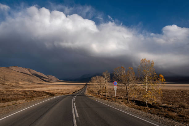 road asphalt mountains clouds sky trees storm stock photo
