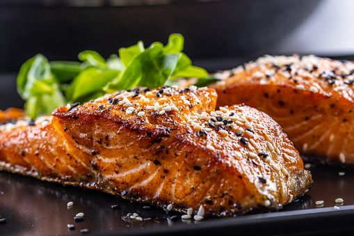 Two salmon fillets baked until crispy with sesame - Close up.
