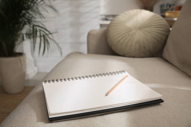 istock Notebook and pencil on light grey sofa in living room 1433811777
