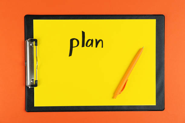 istock Clipboard with word Plan and pen on orange background, top view 1433812010