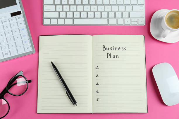 istock Flat lay composition of notebook with words Business Plan on pink background 1433812191