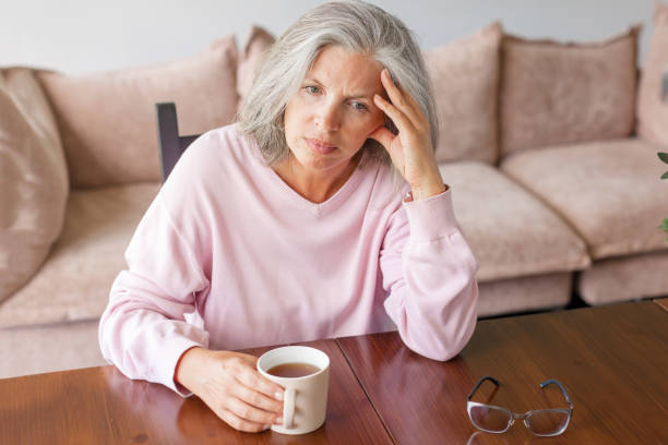 istock Sad pensive middle age woman looking down depressed sitting on the sofa 1433814644