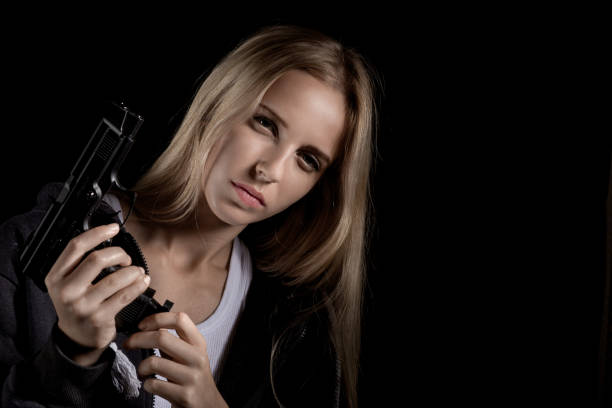 Woman shooting with the gun isolated on black background