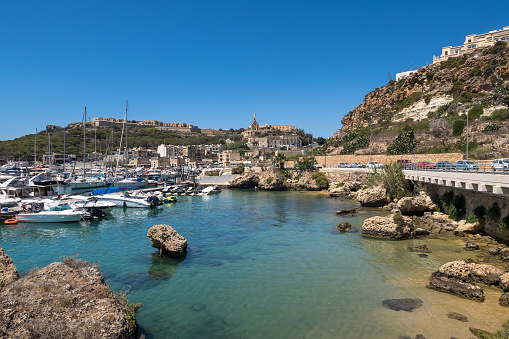 Beautiful shoreline on Gozo, Malta with boats anchored. Summer weather with clear blue sky