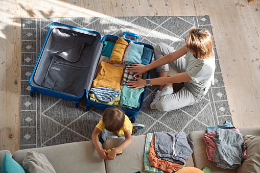 Mother and child are packing things in a suitcase together. Family relocation, flight from the country, closed borders.