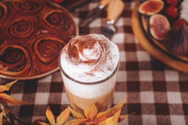 Pumpkin spice whipped latte in glass. Hot autumn drink beverage. Nearby delicious pie and appetizers fruits and cheese. stock photo