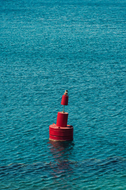 Big red iron navigational buoy with signaling light floating on sea. stock photo