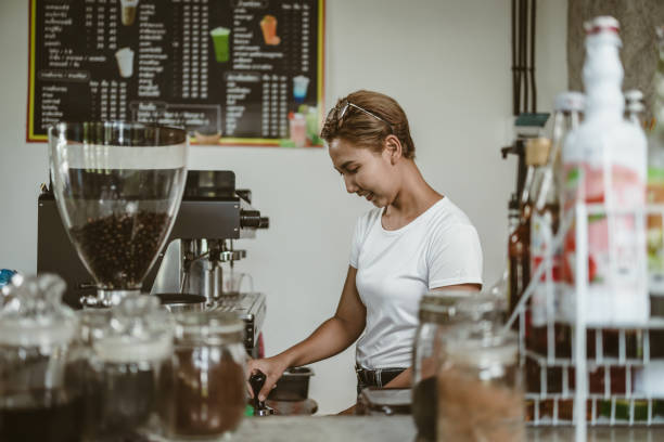 istock Barista using a tamper to press ground coffee into a portafilter. Coffee maker concept. 1433848314