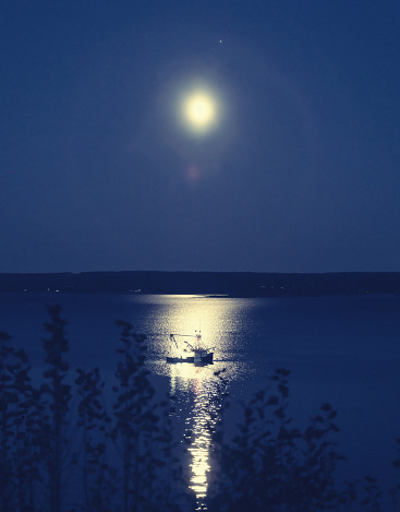 A fishing boat is moored in the light of the Full Moon.