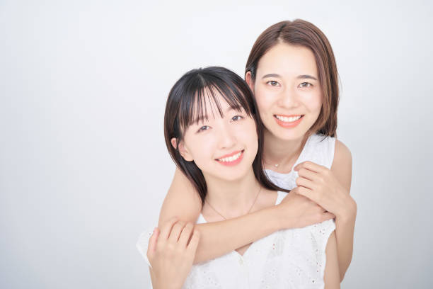 Two women wearing white sleeveless and posing in the photo