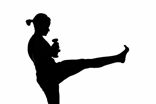 Female martial artist kicking with hand weights.